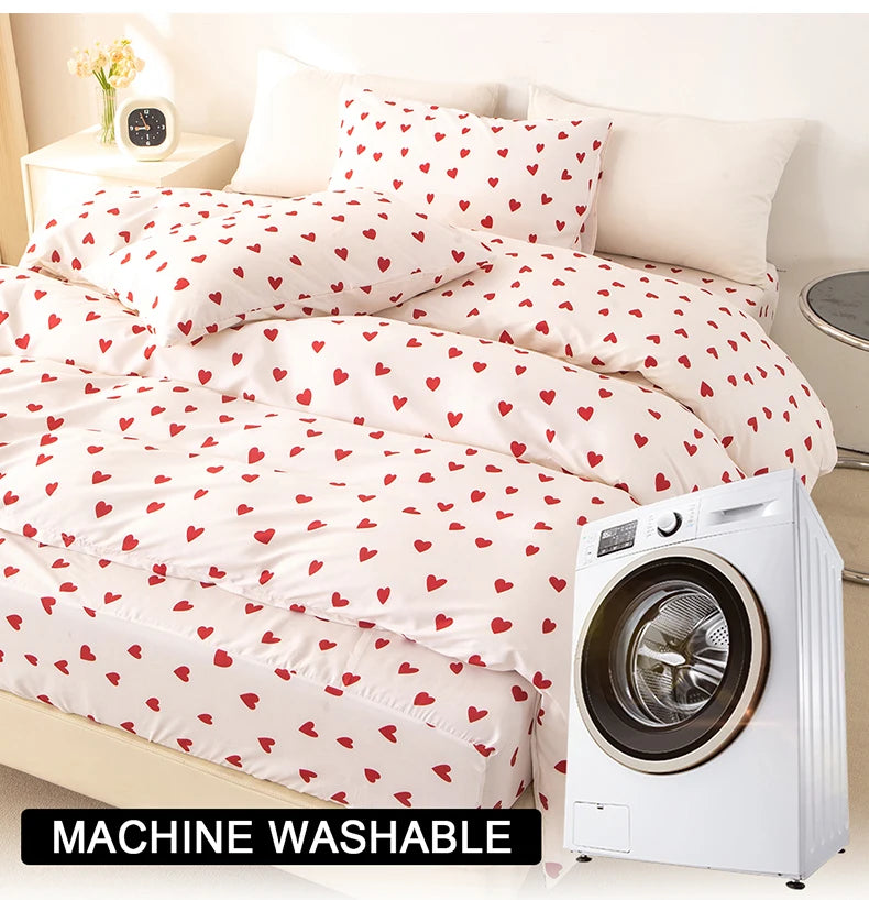 White duvet cover and pillow cases with a red heart print on a bed, next to a white washing machine.
