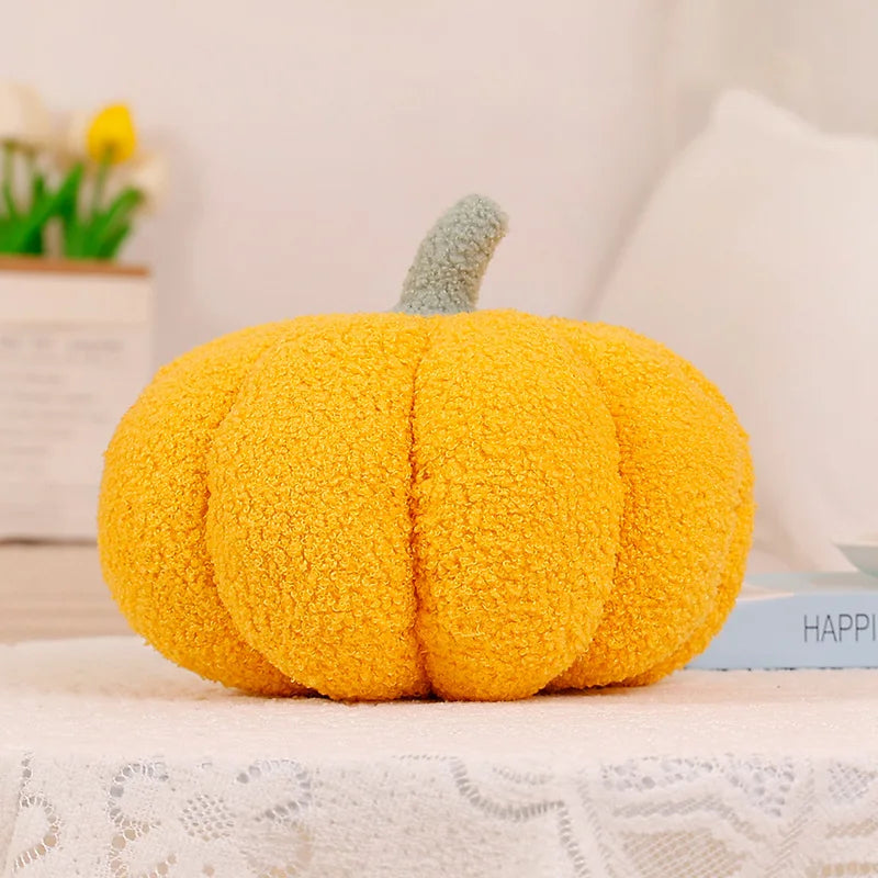 A bright yellow, fuzzy pumpkin shaped throw pillow with a green stem resting on a white lace surface.