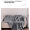 A soft gray flannel throw blanket draped over a light-colored sofa in a bright living room setting.