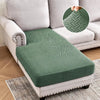 A green jacquard stretch sofa cushion cover placed on a light gray sofa.