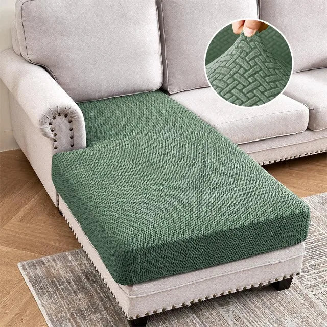 A green jacquard stretch sofa cushion cover placed on a light gray sofa.