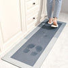 A rectangular gray floor mat with the word HOME embossed on it is placed on a light tile floor near a white cabinet.