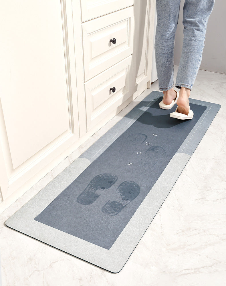 A rectangular gray floor mat with the word HOME embossed on it is placed on a light tile floor near a white cabinet.