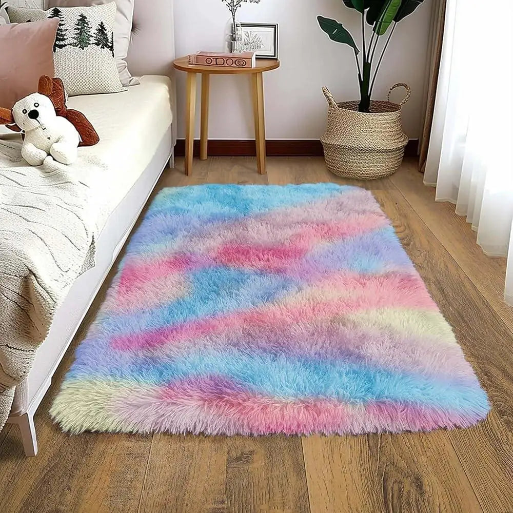 A colorful faux fur area rug featuring pink, blue, and yellow hues placed on a wooden floor.