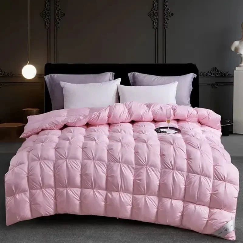 Pink quilted duvet with white pillows displayed on a dark bed against a gray wall.