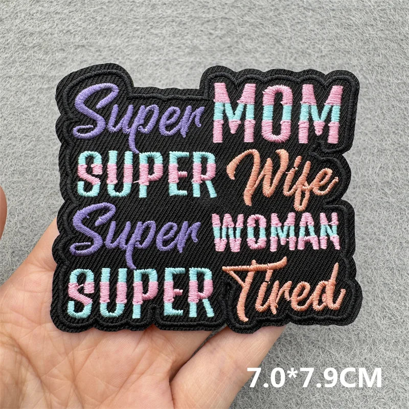 Black embroidered patches with purple and pink text reading Super Mom Super Wife Super Woman Tired