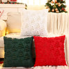 A set of three textured throw pillows in white, dark green, and red velvet are displayed on a white sofa.