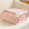 A pink checkered fleece throw blanket folded neatly on a white textured surface.