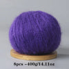 A ball of vibrant purple mohair yarn resting on a wooden base.
