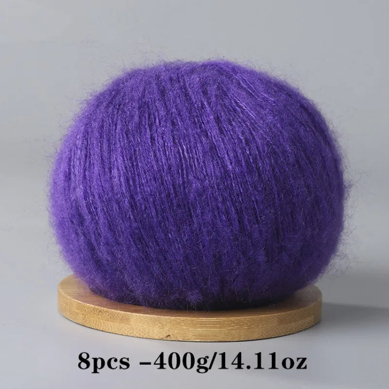 A ball of vibrant purple mohair yarn resting on a wooden base.
