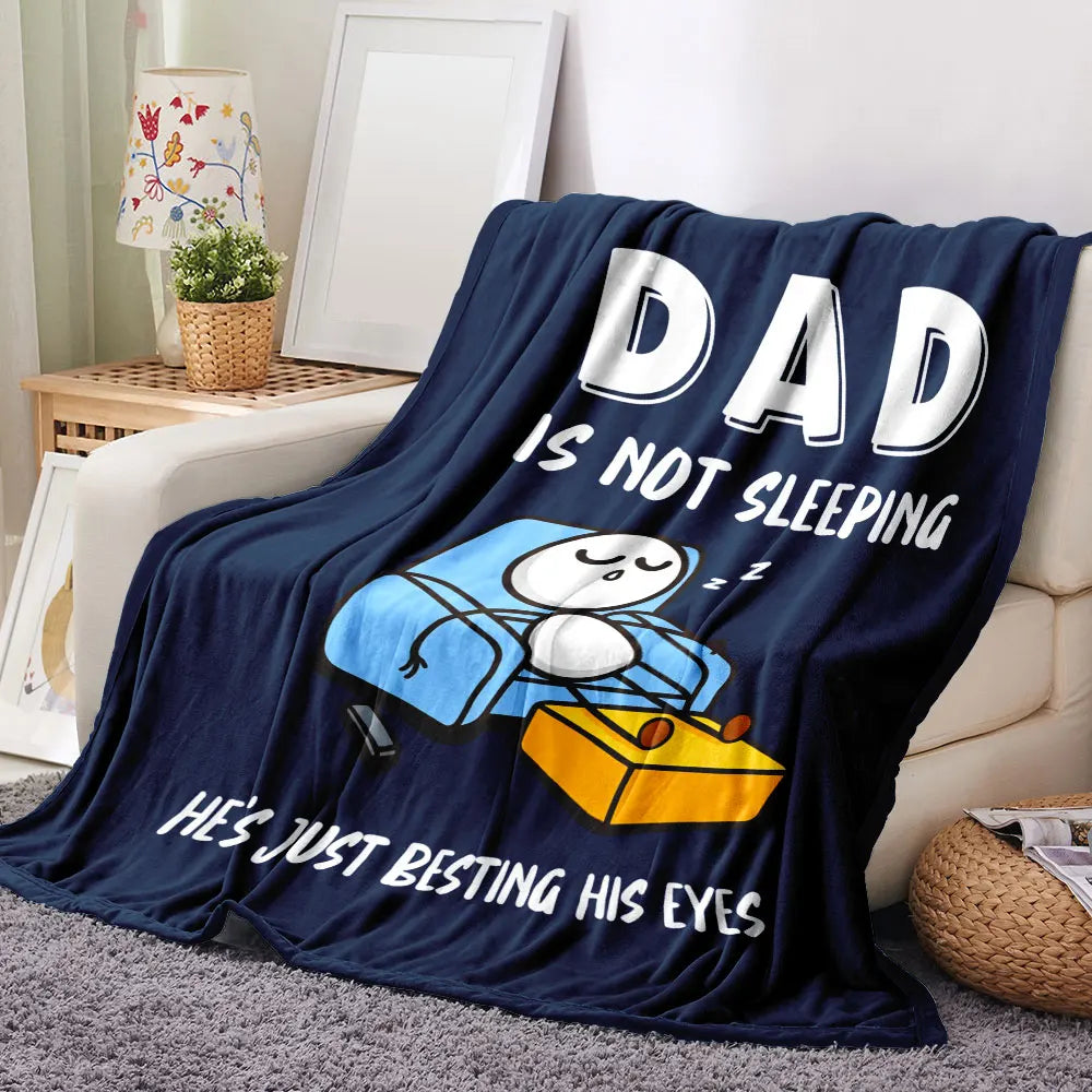 A dark blue blanket featuring a cartoon of a dad who is not sleeping and is besting his eyes.