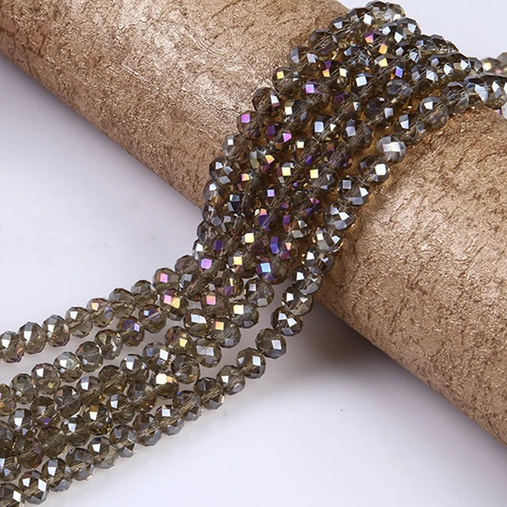 A strand of faceted brown and purple glass beads is unwrapped on a roll of tan paper.