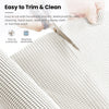 A hand is using a silicone non-slip drawer liner to trim and clean a fabric surface.