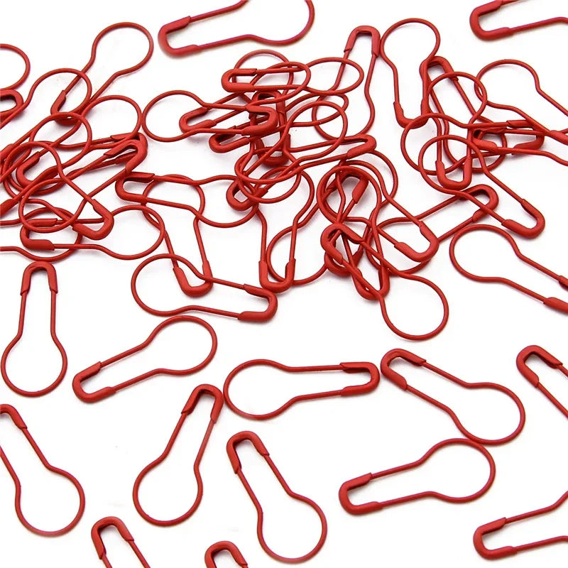 A pile of red safety bulb pins for knitting and sewing used for crafting projects.