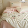 A pink embroidered tulip duvet cover set with a matching pillow and sheet in a light pink color.