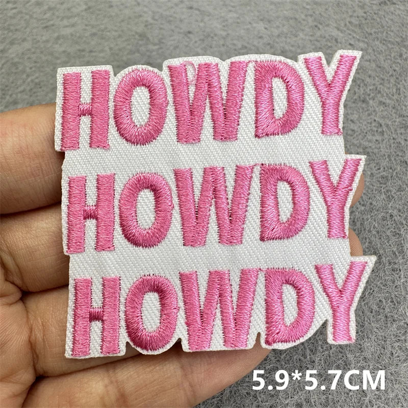 Four pink embroidered patches with the word HOWDY stitched onto a white fabric background