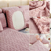 A close-up view of a pink plush velvet sofa cover with a quilted texture and anti-slip backing.