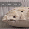 A close-up of a cream-colored plush throw pillow cover featuring a subtle geometric pattern and fringed edges.