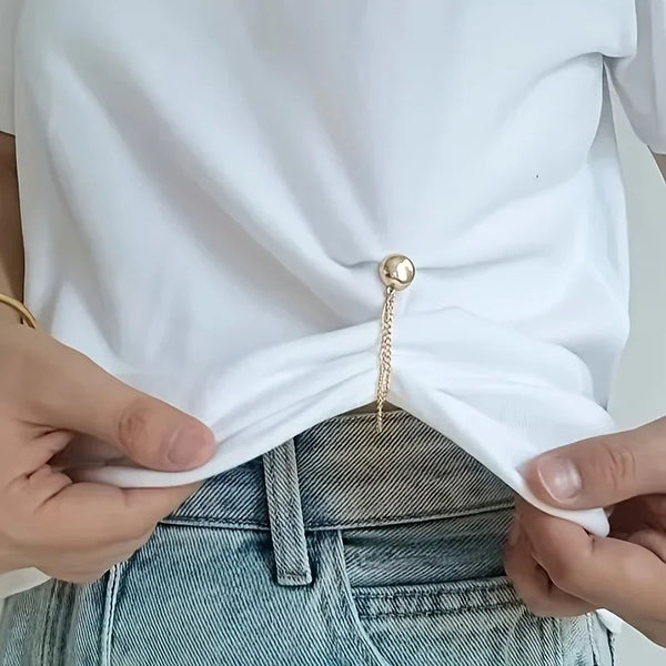 Hands adjusting the hem of a white t-shirt over denim jeans.