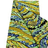 Close-up of a yellow and green African wax print fabric folded to show the pattern.