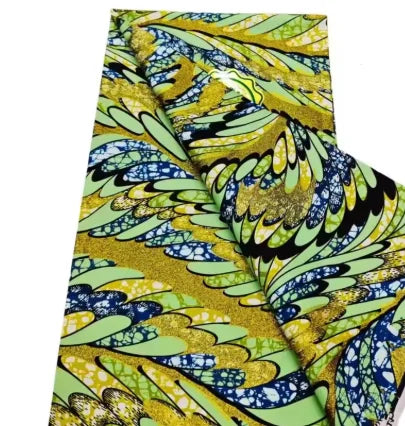 Close-up of a yellow and green African wax print fabric folded to show the pattern.