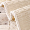 A close-up of a white, textured cozy non-slip sofa cover with a quilted appearance.
