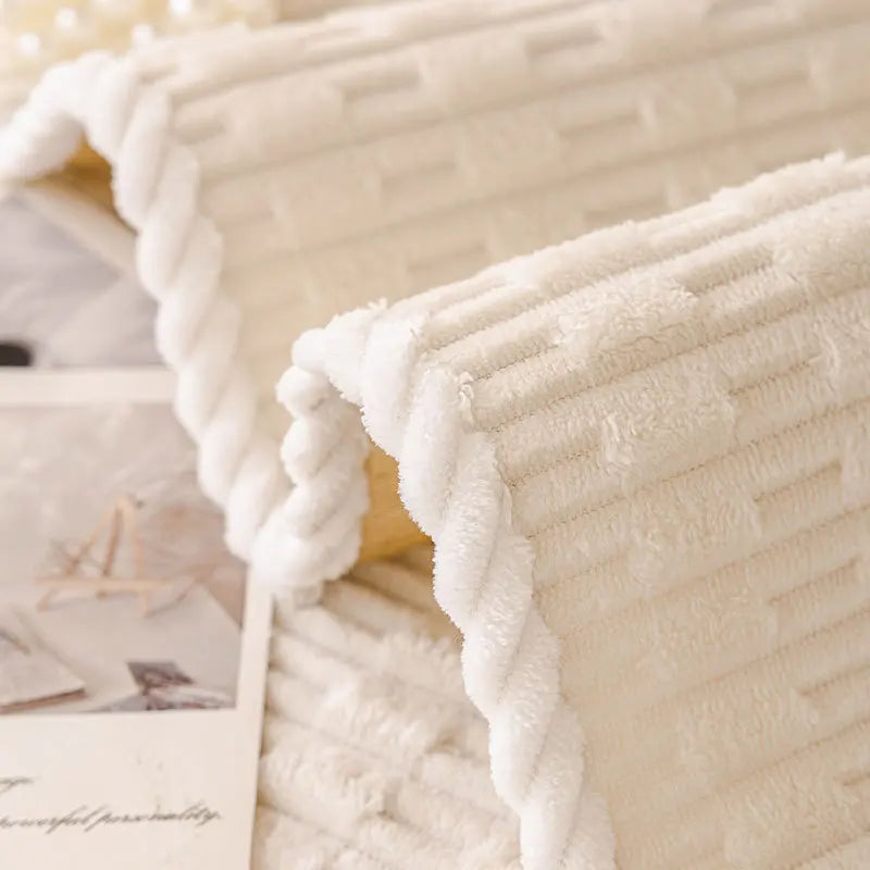 A close-up of a white, textured cozy non-slip sofa cover with a quilted appearance.