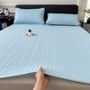 Light blue cooling ice silk bed pad with quilted texture placed on a bed.