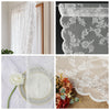 Close-up of vintage floral lace curtains and a white flower resting on a sheer white fabric.