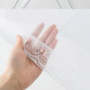 A hand is holding a white mesh insect and fly protection cover, showing the delicate lace detailing.