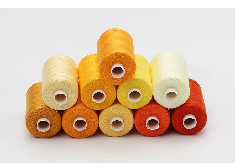A collection of ten colored polyester sewing thread spools in shades of orange, yellow, and red.