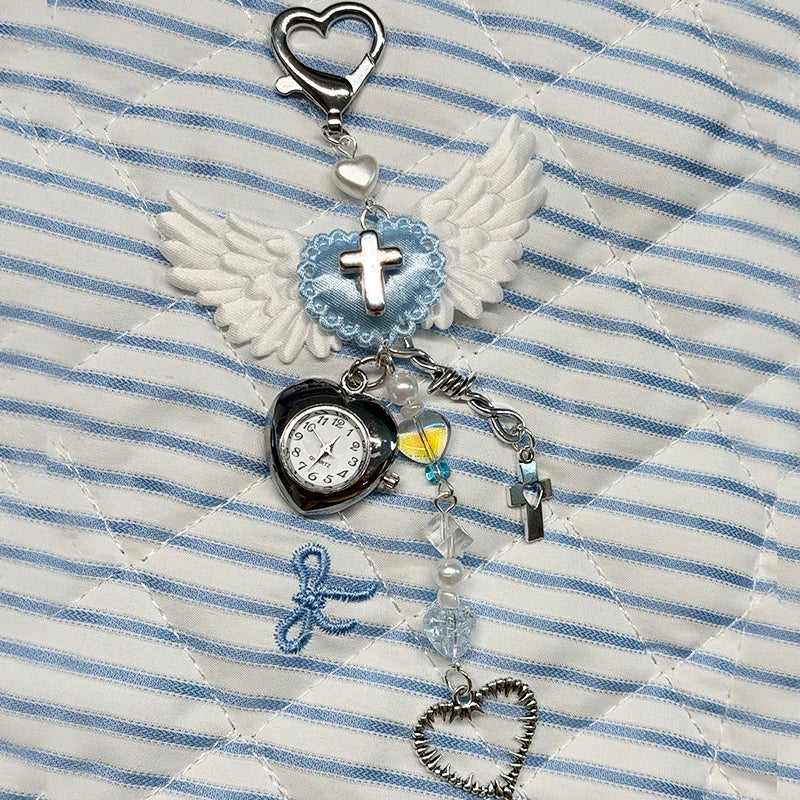 Silver and blue heart-shaped keychain featuring an adjustable clock and a white feather design