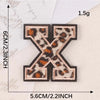 A black iron-on patch shaped like the letter X with a leopard print design.