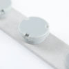 A close-up view of a gray magnetic embroidery hoop set component on a white strip.
