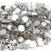 A close-up view of clear and silver crystal AB flatback rhinestones scattered on a white background.