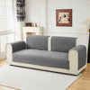 A modern gray geometric quilted sofa cushion cover displayed on a light-colored sofa in a bright room.