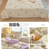 A light yellow and white cartoon pattern quilt is displayed on a bed with pink accents.