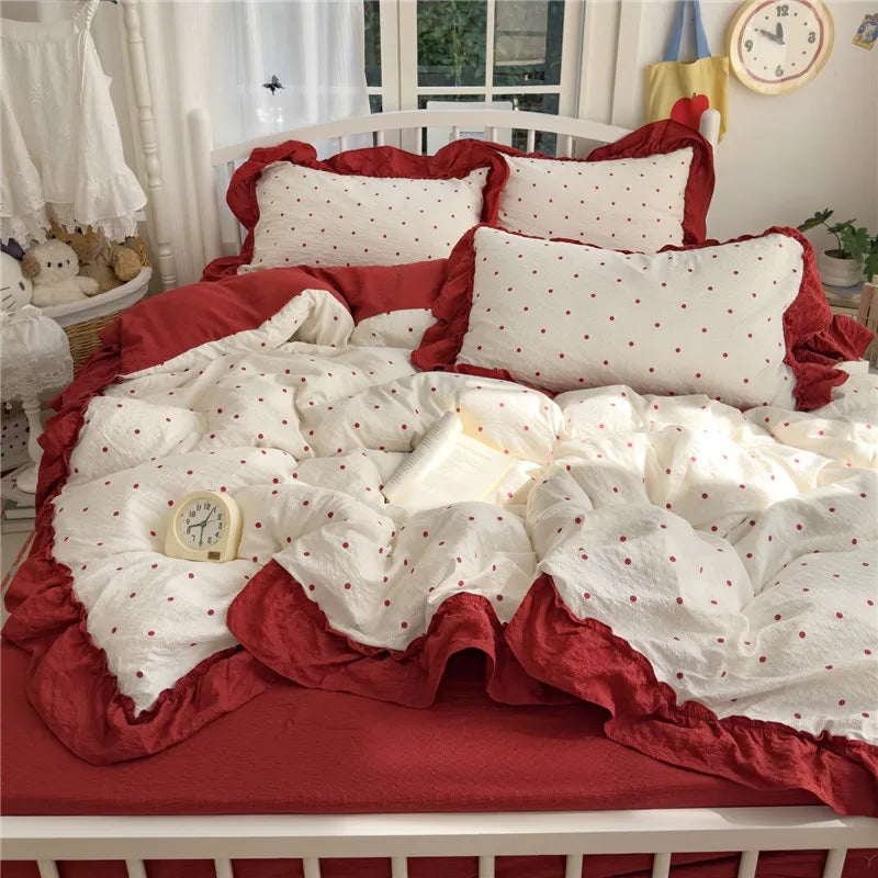 A princess style bedding set featuring white fabric with red polka dots and a deep red ruffle on a white bed frame.