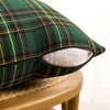 A dark green and yellow tartan plaid decorative throw pillow cover shown on a wooden surface.