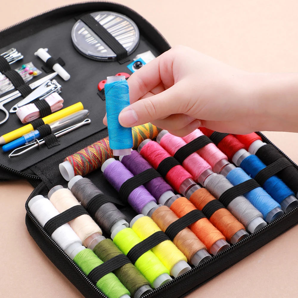 A hand is holding a spool of bright blue thread inside a black sewing kit containing various threads and tools.