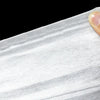A close-up view of a white disposable non-woven beauty and salon sheet being held by a finger.