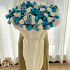 A hand knitted floral rose bouquet throw blanket featuring blue and white flowers.