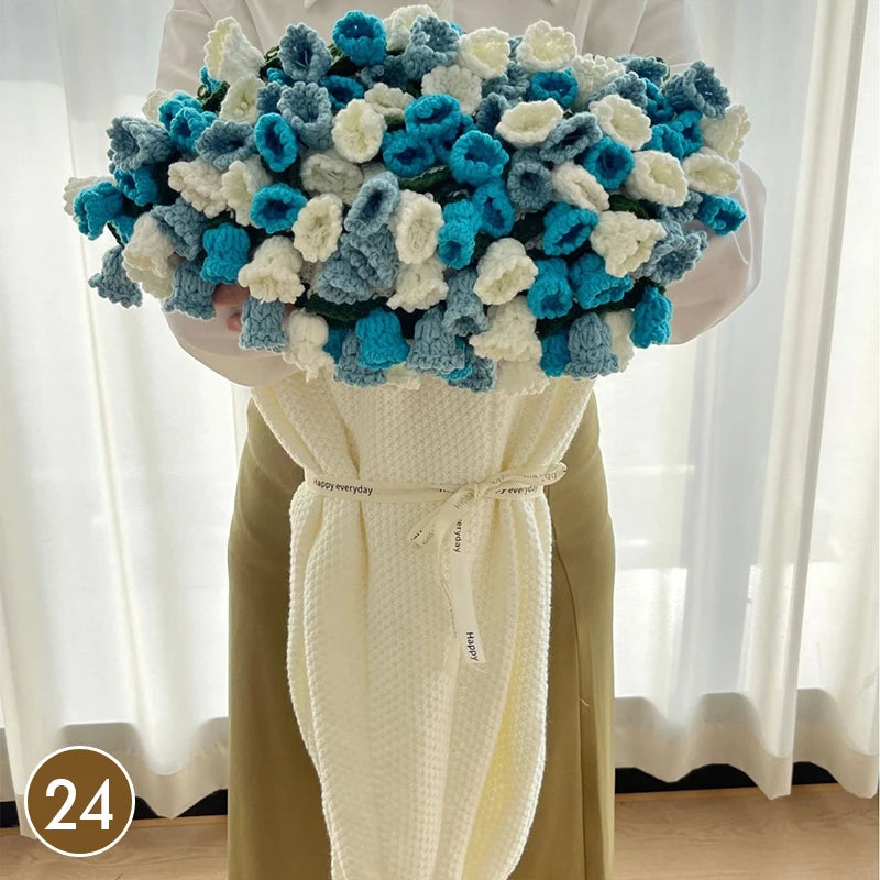 A hand knitted floral rose bouquet throw blanket featuring blue and white flowers.
