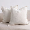 A close-up of a white textured boucle throw pillow resting on a light-colored sofa.