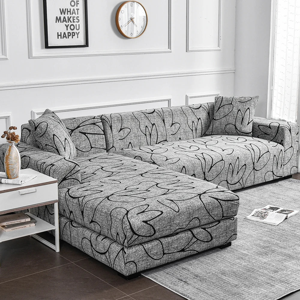 A gray elastic sofa cover protector with a black flower print pattern displayed on a sofa.