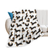 A white flannel blanket featuring a repeating pattern of black and orange dachshund silhouettes.