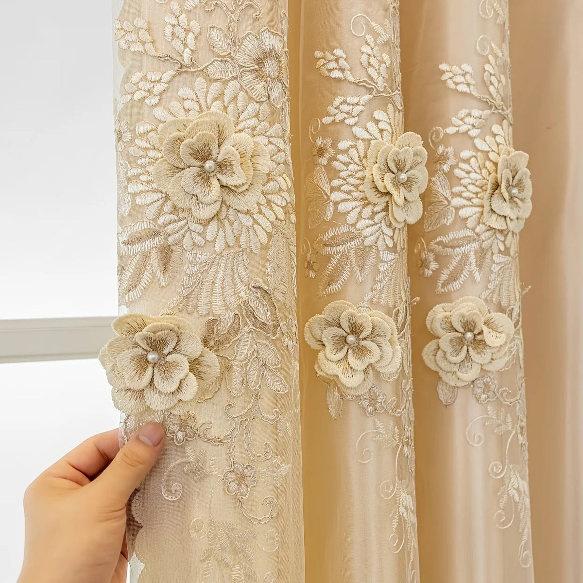 Close-up of a sheer beige lace curtain with floral embroidery hanging from a rod.