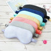 A collection of silk sleep masks in various pastel and dark colors laid out on a white wooden surface.