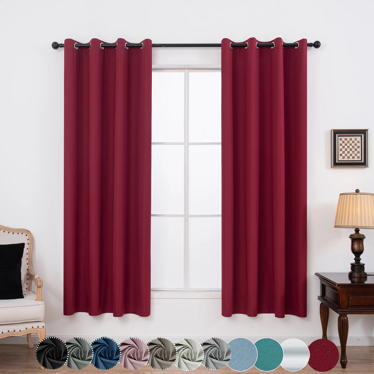 A set of two deep red blackout grommet curtains hanging in a window frame.