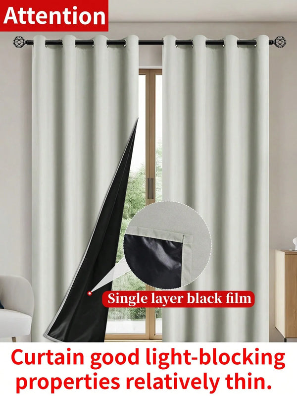 Single layer black film curtain in light gray blocking natural light through a window.